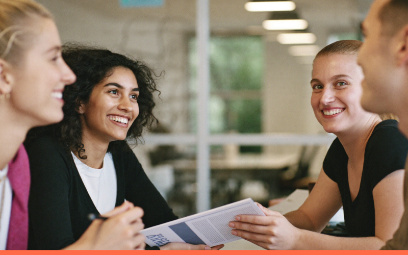 Grupo de jovens trainees colaborando e sorrindo em um escritório