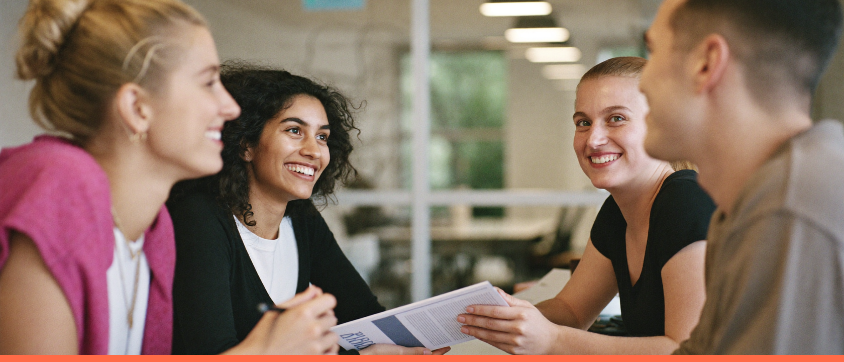 Grupo de jovens trainees colaborando e sorrindo em um escritório