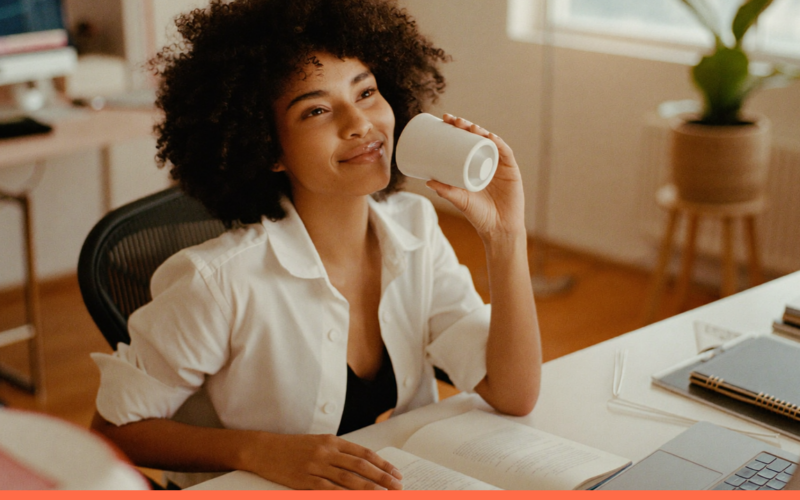 Profissional tranquila com uma xícara de café no trabalho, representando salário emocional