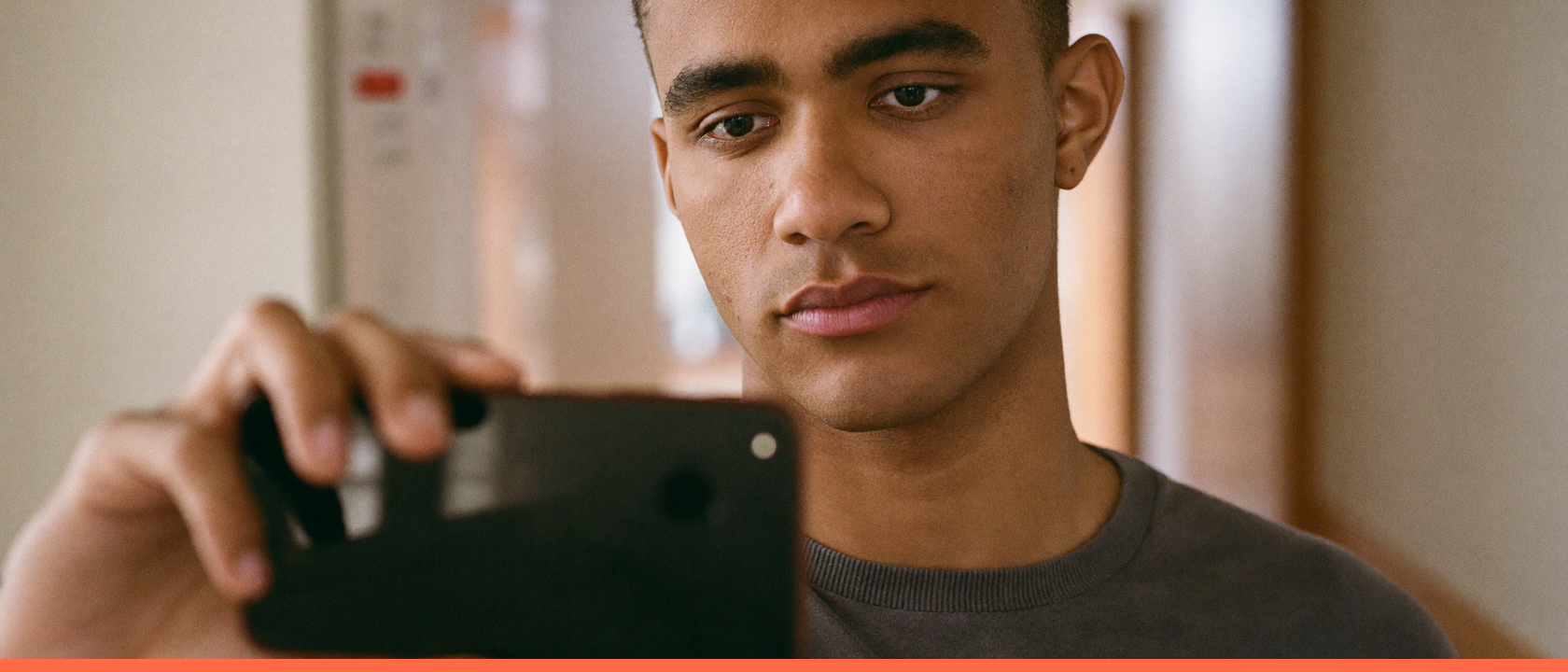 Jovem profissional consultando o celular durante uma pausa curta no corredor do escritório